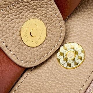 Close-up of a beige and brown leather handbag magnetic snap closure with gold hardware
