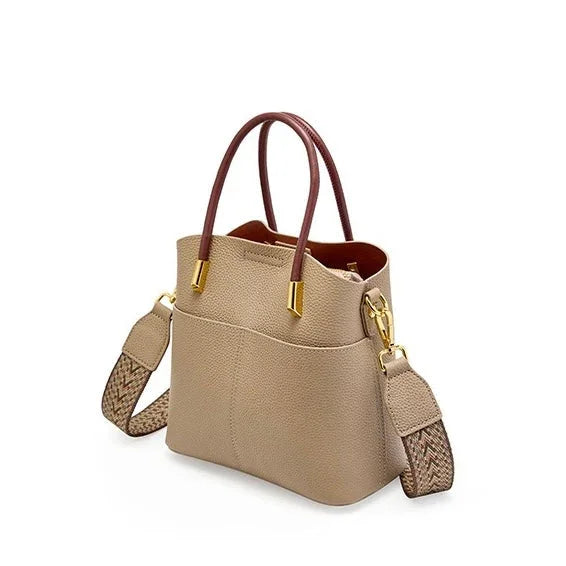 Beige leather handbag with brown handles, gold hardware, and wide braided shoulder strap