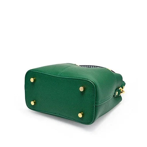 Green leather handbag with gold studs on bottom, photographed against white background