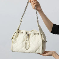 Quilted white leather handbag with chain strap held in hand against plain background