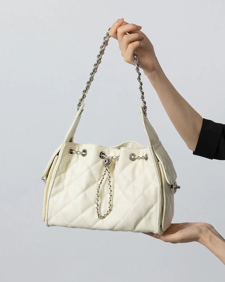 Quilted white leather handbag with chain strap held in hand against plain background