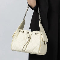 Woman holding quilted white shoulder bag with chain strap and silver hardware