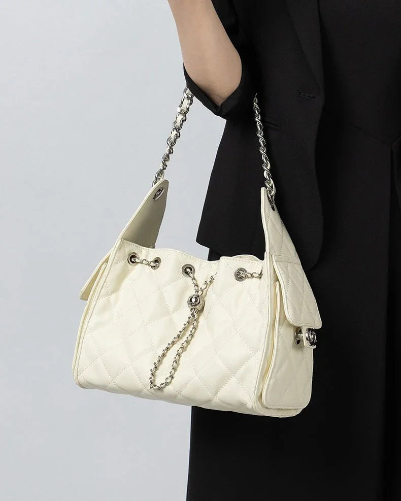 Woman holding quilted white shoulder bag with chain strap and silver hardware