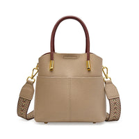 Taupe leather handbag with brown handles, gold hardware, and woven shoulder strap