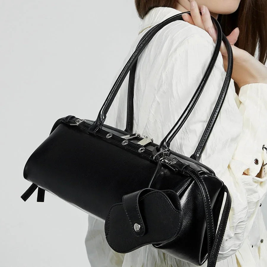 Woman carrying black leather handbag with double straps and coin pouch, white textured blouse