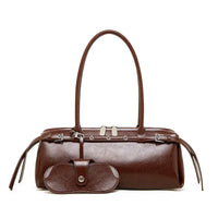 Brown leather handbag with long handles and matching glasses case on white background