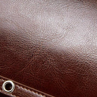 Brown leather texture with metal eyelet detail, close-up.