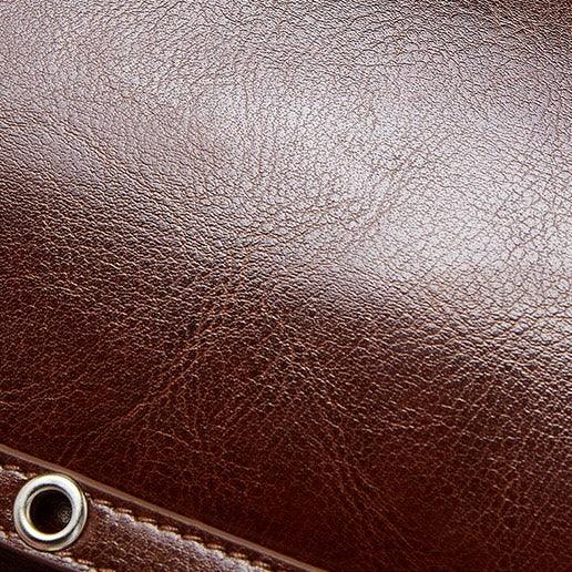 Brown leather texture with metal eyelet detail, close-up.