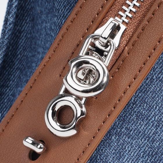 Close-up of silver zipper on brown leather and blue denim bag