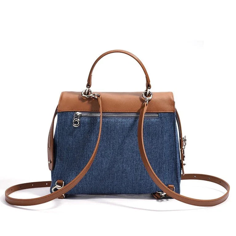 Denim and brown leather crossbody bag with top handle and zippered pocket on white background