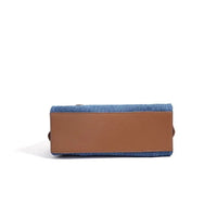 Rectangular blue denim handbag with brown leather bottom on white background