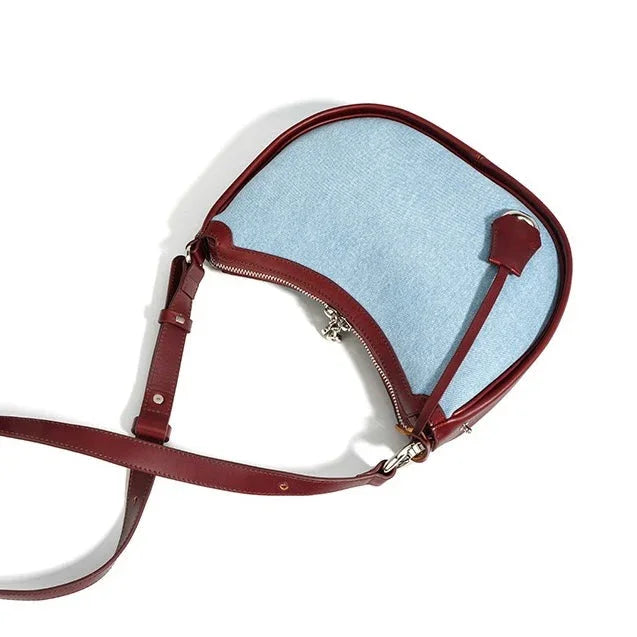 Light blue and burgundy crossbody bag with curved shape on white background