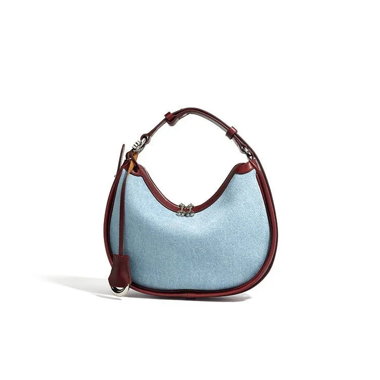 Light blue hobo handbag with brown leather trim and silver clasp on a white background