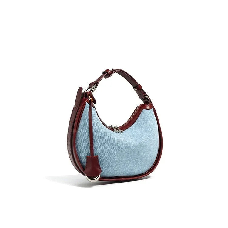 Light blue denim hobo bag with brown leather trim and shoulder strap on white background
