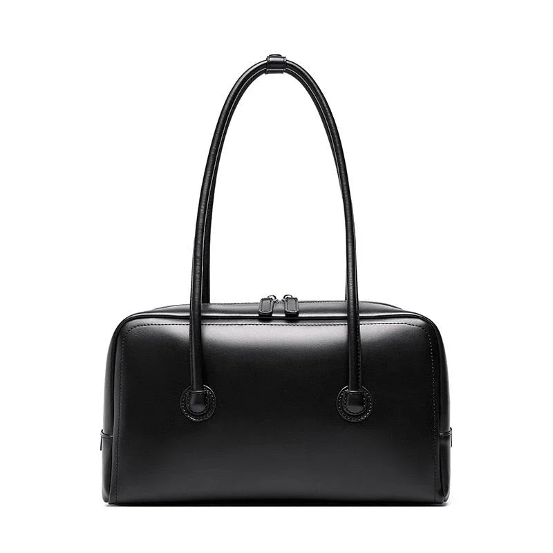 Black leather handbag with double handles and zip closure on white background