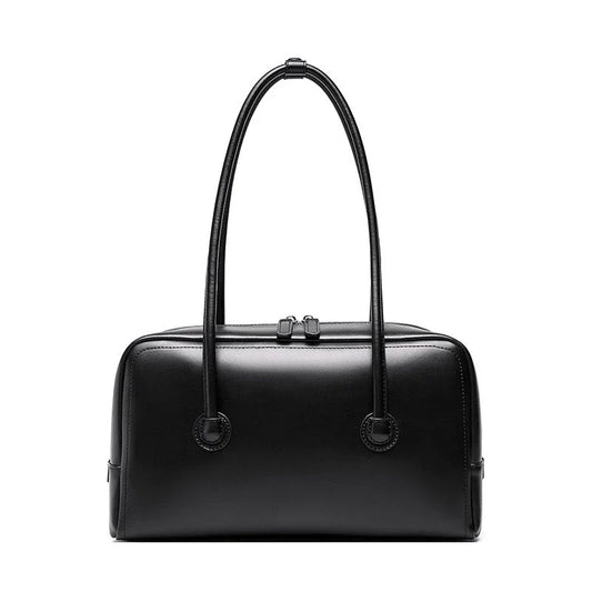 Black leather handbag with double handles and zip closure on white background