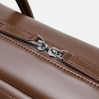 Close-up of brown leather bag with silver zipper on white background