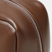 Close-up of brown leather bag with silver zipper detail