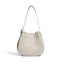 Beige leather shoulder bag with adjustable strap on white background