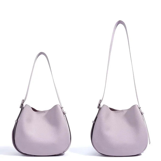 Two light purple leather handbags with shoulder straps on a white background