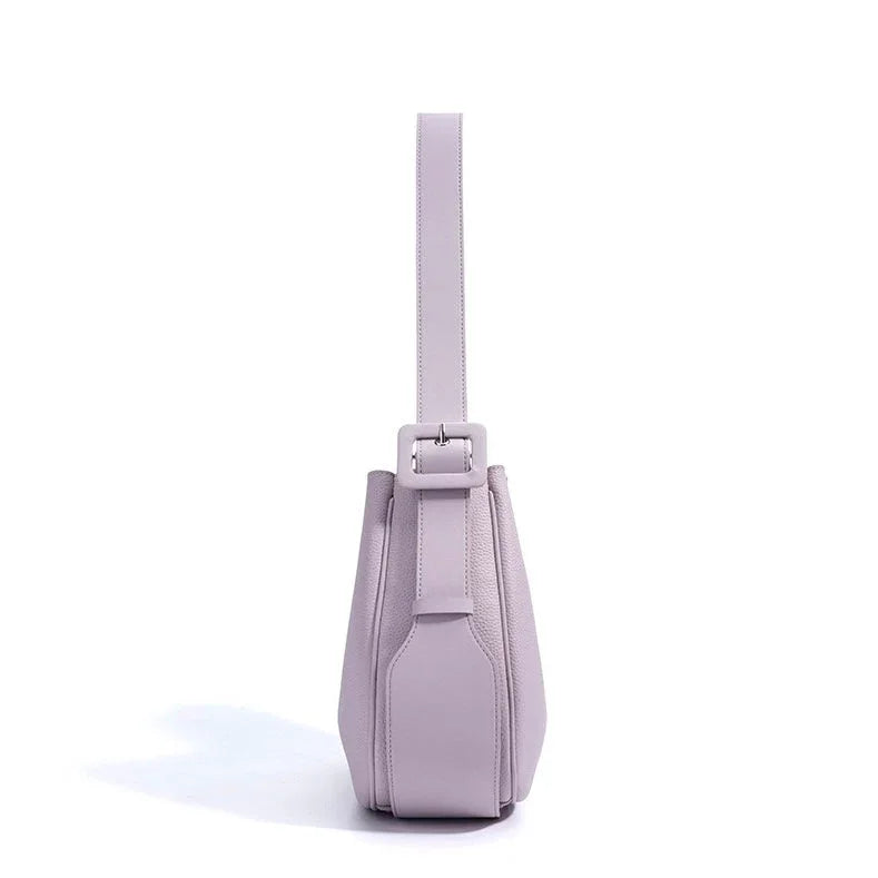 Side view of a light purple leather handbag with a wide strap and buckle detail