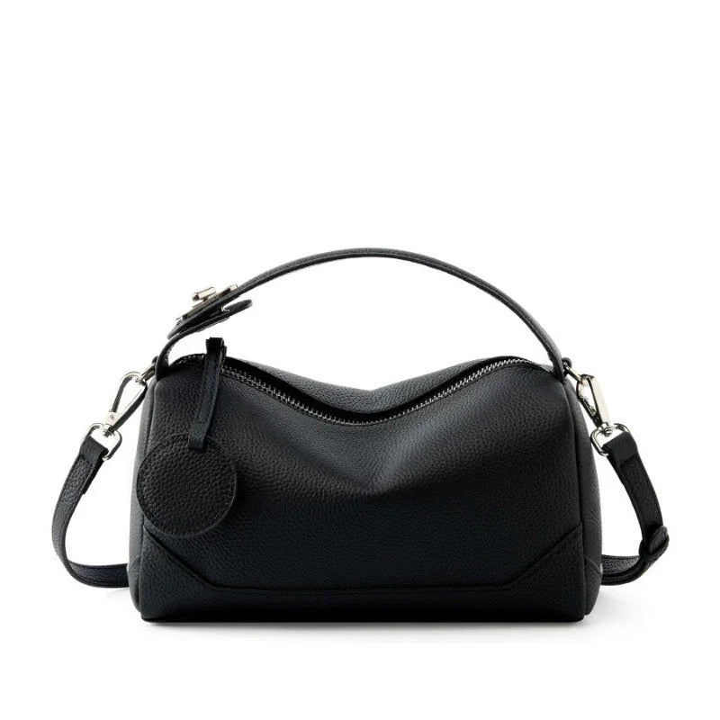 Black leather handbag with top handle and detachable shoulder strap on white background