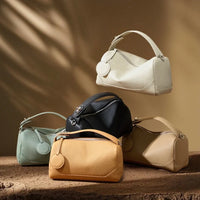 Assorted leather handbags in neutral colors on textured surface with soft brown background