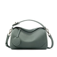 Sage green leather handbag with top handle, detachable strap, and round zipper pull