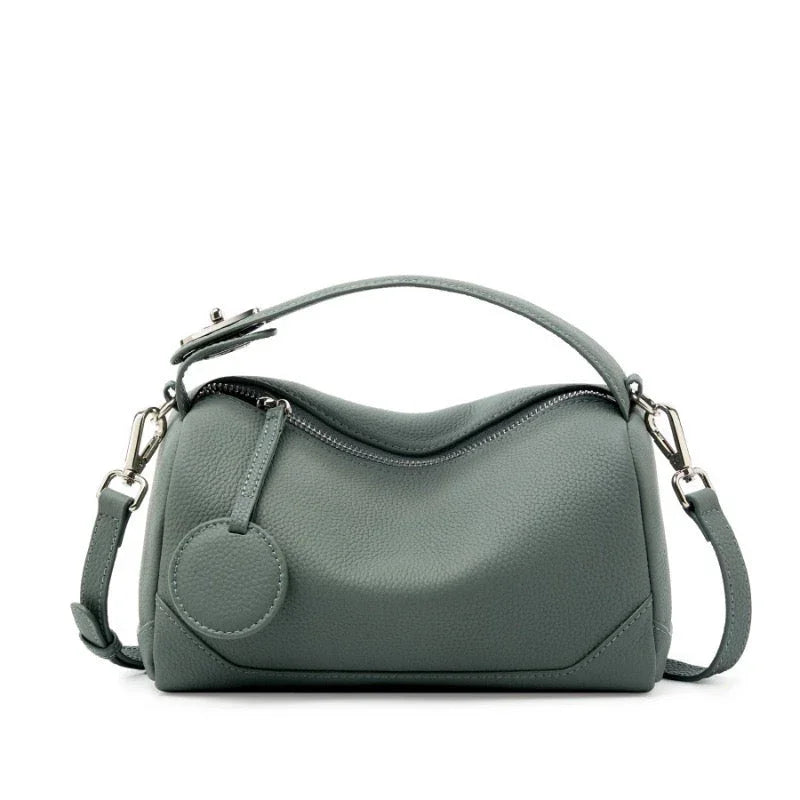 Sage green leather handbag with top handle, detachable strap, and round zipper pull