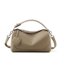 Taupe leather handbag with zipper closure, top handle, and adjustable shoulder strap