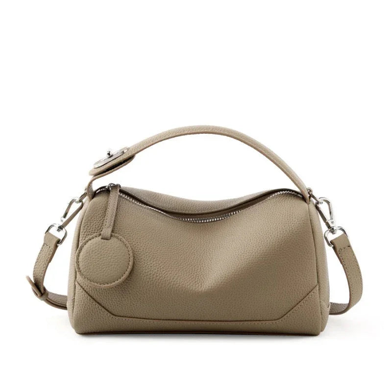 Taupe leather handbag with zipper closure, top handle, and adjustable shoulder strap