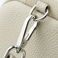 Close-up of silver lobster clasp on textured cream leather handbag