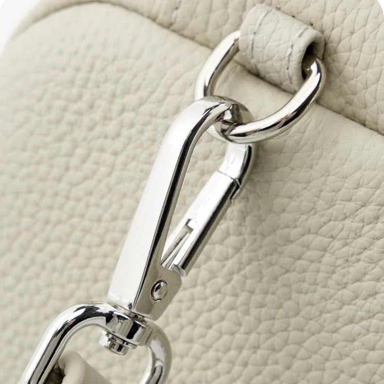 Close-up of silver lobster clasp on textured cream leather handbag