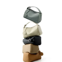 Stack of five leather handbags in neutral colors on a white background