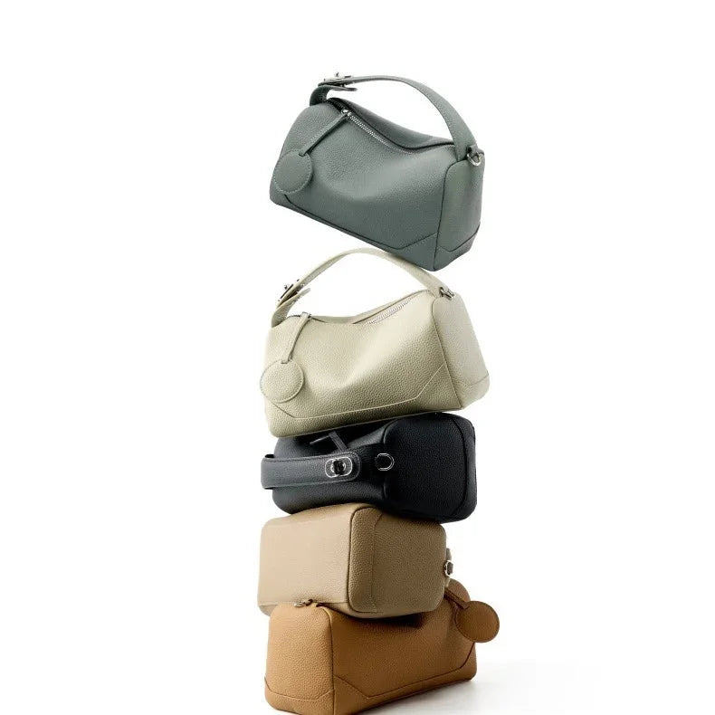 Stack of five leather handbags in neutral colors on a white background