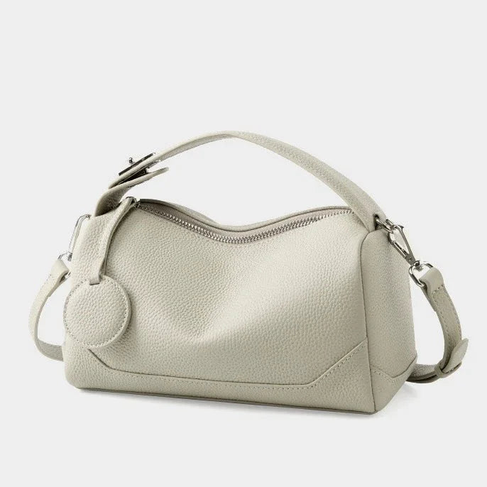Light gray leather handbag with top handle, zipper closure, and textured finish
