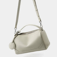 Beige leather crossbody bag with textured finish and adjustable strap on white background