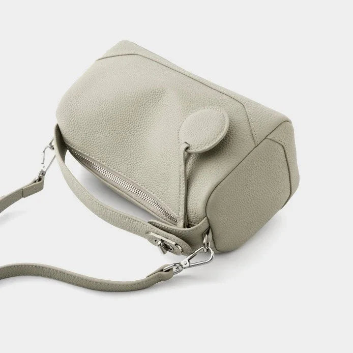 Light gray leather crossbody bag with zipper and shoulder strap on white background