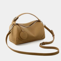 Tan leather crossbody handbag with top handle and silver zipper on a white background