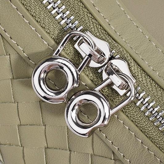 Close-up of silver zipper pulls on a woven sage green leather bag