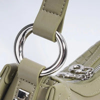 Close-up of sage green handbag with silver ring detail and zipper accents