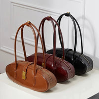 Three oval leather handbags in brown, burgundy, and black on a white table