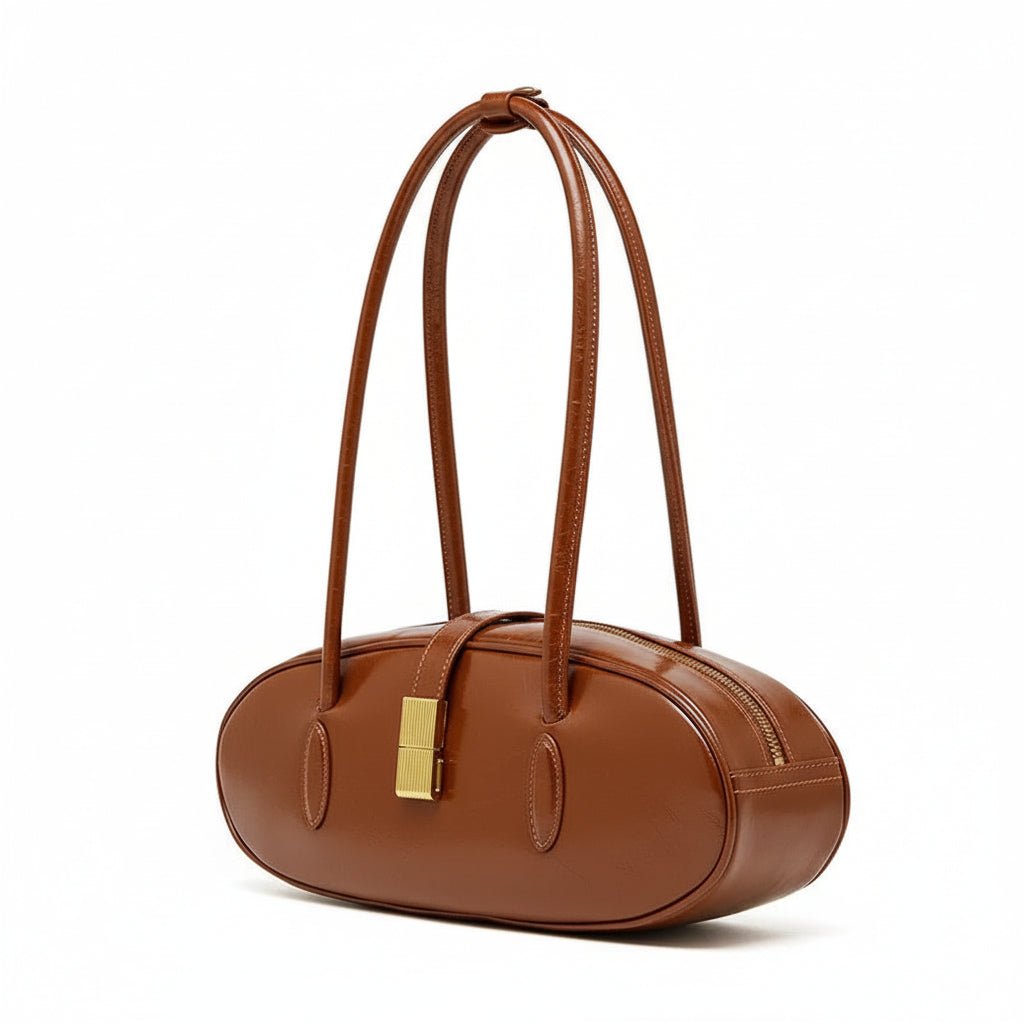 Brown leather oval handbag with double straps and gold clasp on white background