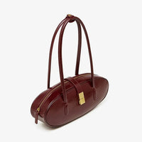 Oval burgundy leather handbag with gold clasp and dual shoulder straps on white background