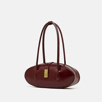 Burgundy oval-shaped leather handbag with gold clasp and double handles on white background