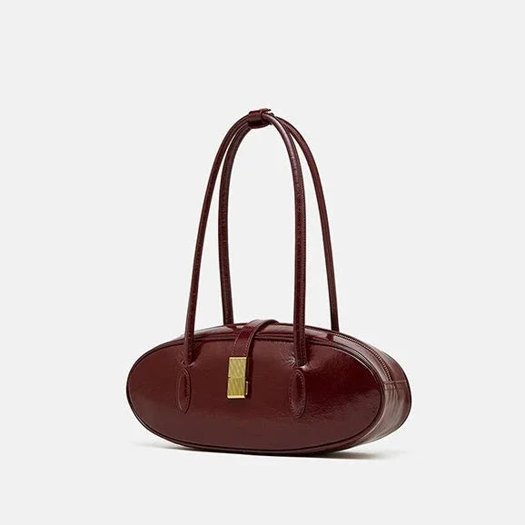 Burgundy oval-shaped leather handbag with gold clasp and double handles on white background