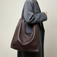 Woman in gray coat carrying large brown leather shoulder bag