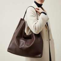Woman wearing brown oversized leather tote bag with brown trench coat