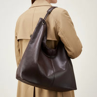Large brown leather shoulder bag on person in tan blazer