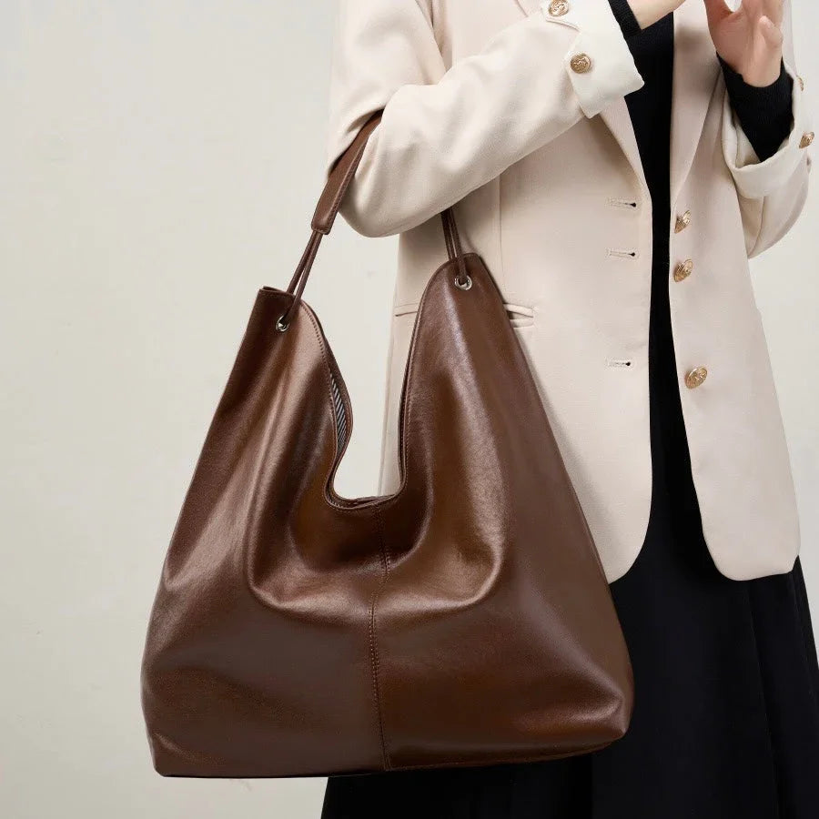Woman in beige blazer holding large brown leather tote bag